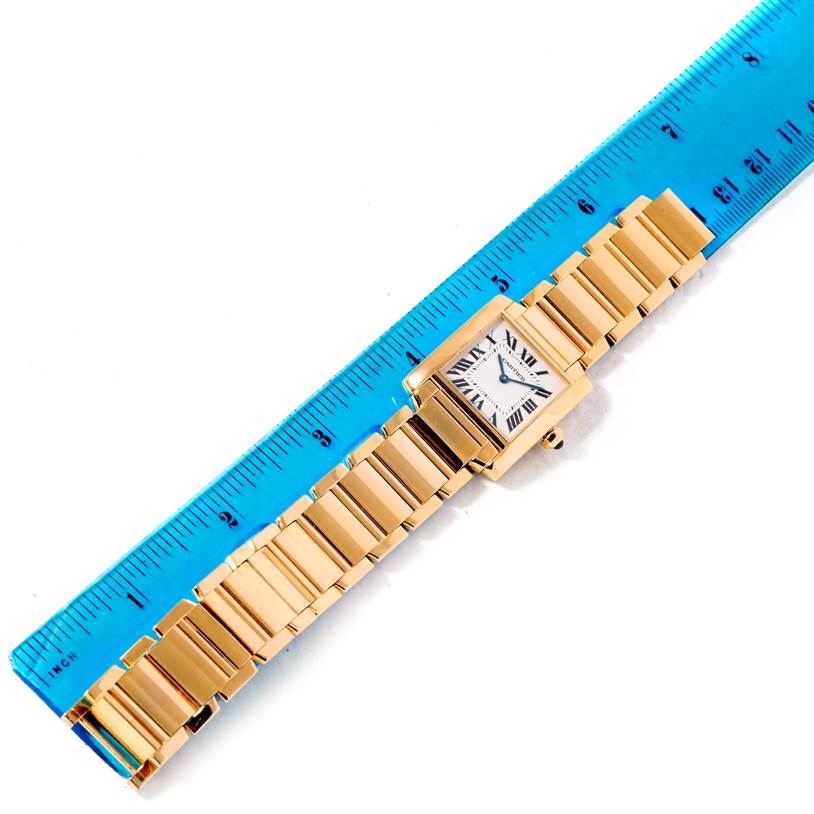 The image shows a Cartier Tank Française watch laid flat next to a blue ruler, highlighting the entire watch and its strap.