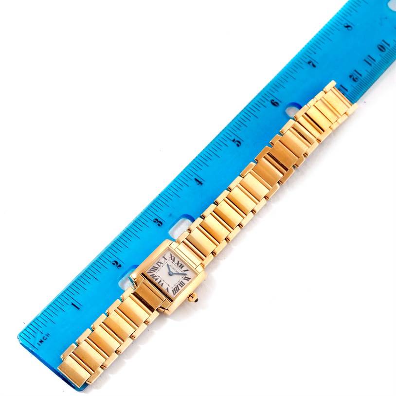 The image shows a Cartier Tank Française watch laid flat next to a blue ruler, showing the full length of the band and face.
