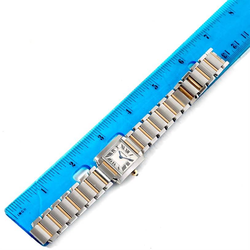 This image shows the entire Cartier Tank Française watch placed alongside a blue ruler, highlighting its length.