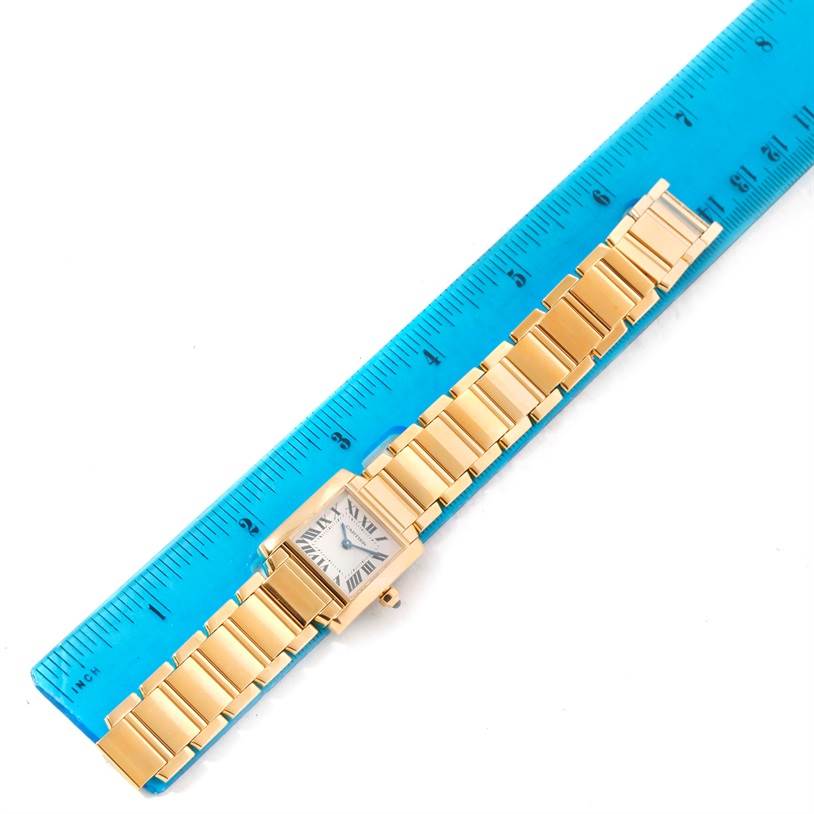 This image shows an overhead view of a Cartier Tank Francaise W50002N2 Women's Yellow Gold Silver Dial W50002N2 Women's Yellow Gold Silver Dial watch, laid next to a blue ruler for measurement.