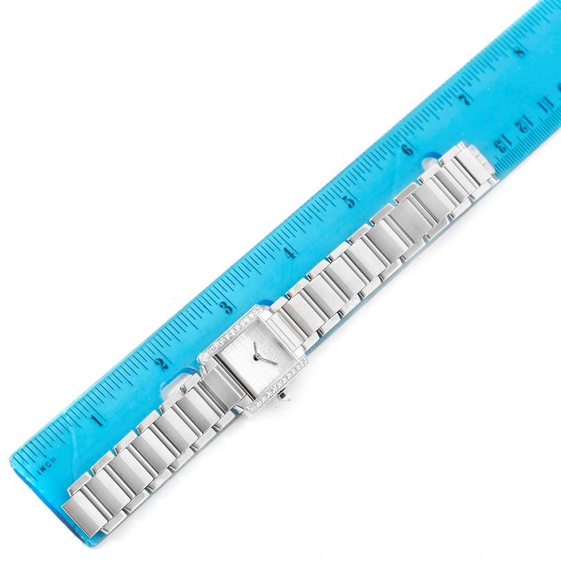 The Cartier Tank Francaise WE1002S3 Women's White Gold Silver Dial WE1002S3 Women's White Gold Silver Dial watch is shown from above, with its metal strap and face next to a blue ruler for measurement.