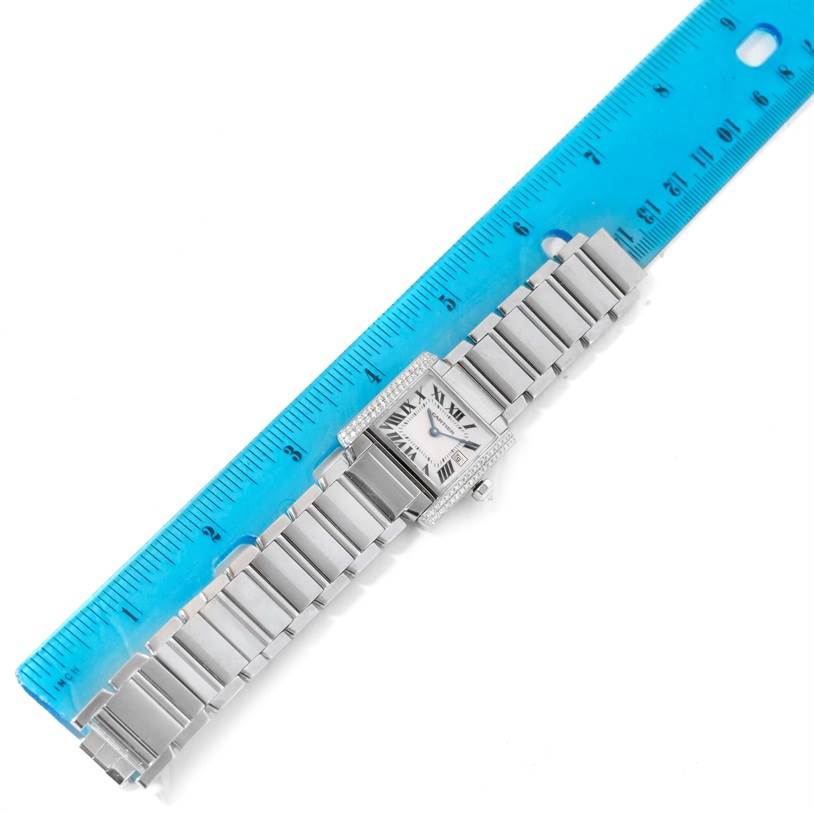 The Cartier Tank Francaise WE1018S3 Women's White Gold Silver Dial WE1018S3 Women's White Gold Silver Dial watch is shown lying flat with the face and metal bracelet fully visible alongside a blue ruler for scale.