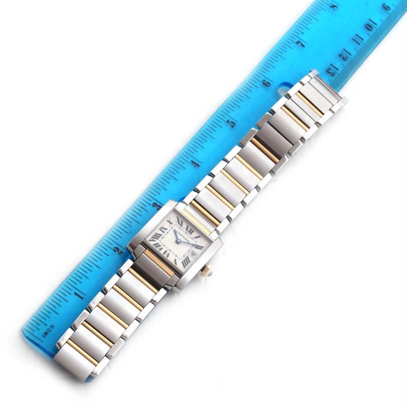 The Cartier Tank Française watch is shown from a top-down angle, lying flat beside a blue ruler.