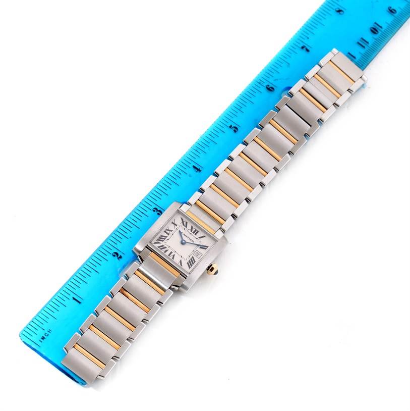The Cartier Tank Francaise W51012Q4 Women's Steel and Gold (two tone) Silver Dial W51012Q4 Women's Steel and Gold (two tone) Silver Dial watch is shown flat with its bracelet extended next to a ruler for size reference.