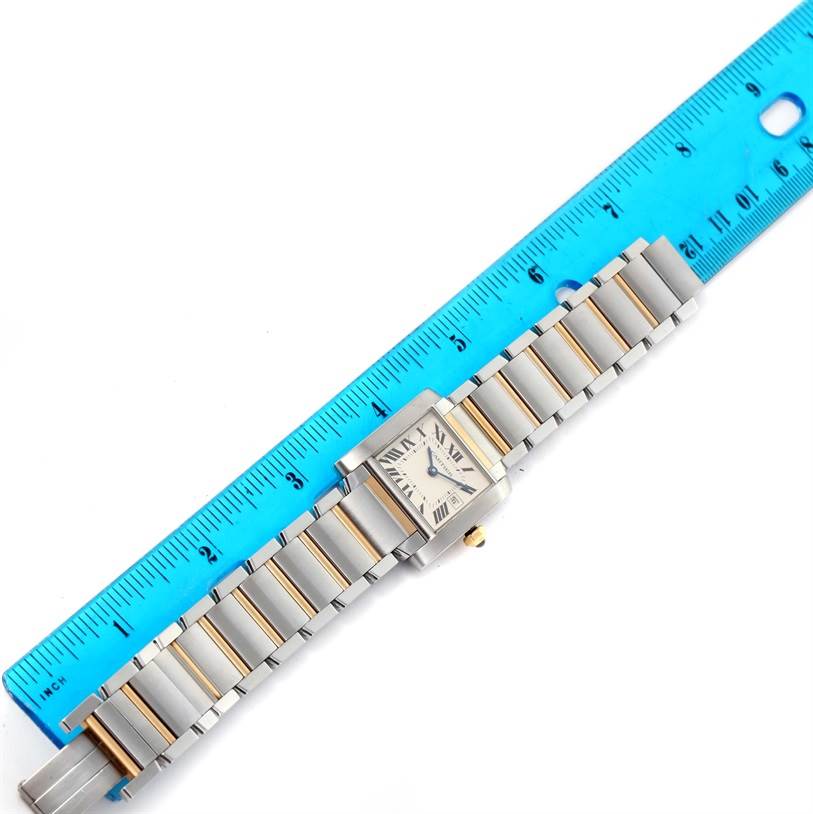 The image shows the Tank Francaise model by Cartier, laid flat with its band and face visible, next to a blue ruler for scale.