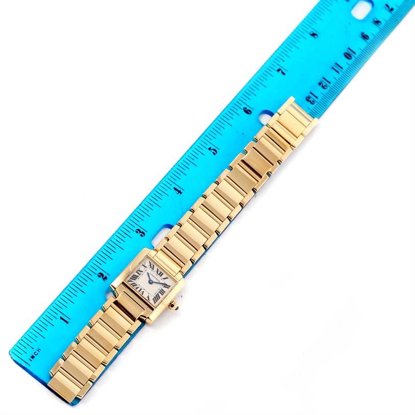 The Cartier Tank Française watch is shown from above, placed alongside a blue ruler for size reference.