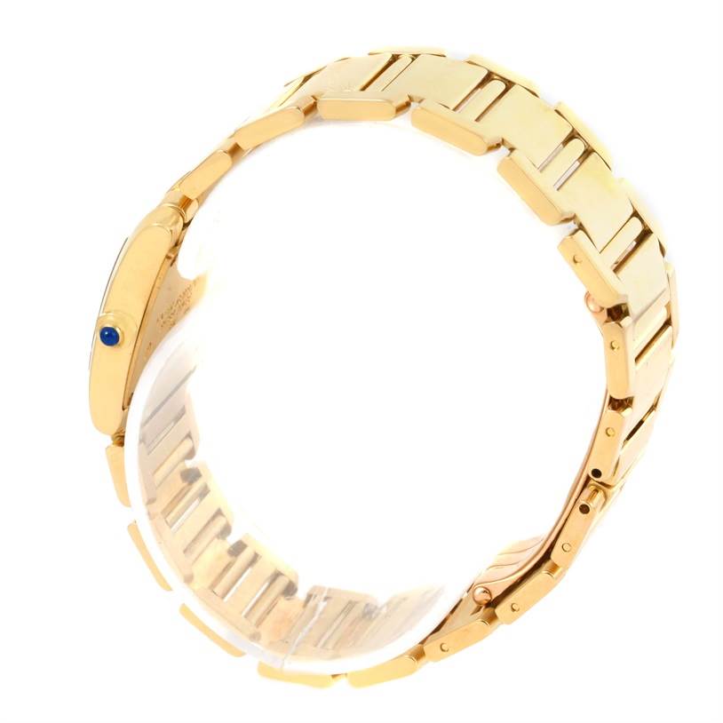 The image shows a Cartier Tank Francaise W50002N2 Women's Yellow Gold Silver Dial W50002N2 Women's Yellow Gold Silver Dial watch viewed from the side, focusing on the gold bracelet and the crown with a blue cabochon.