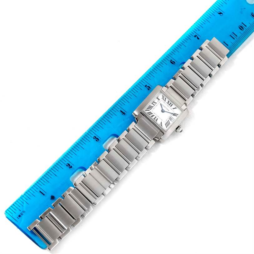 The Cartier Tank Française watch is shown lying flat alongside a ruler, displaying its entire bracelet and face.
