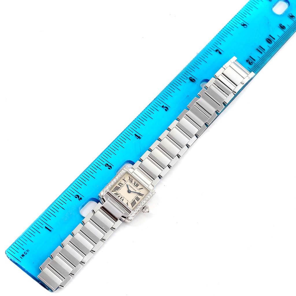 This image shows a top view of a Cartier Tank Francaise WE1002S3 Women's White Gold Silver Dial WE1002S3 Women's White Gold Silver Dial watch next to a blue ruler for scale.