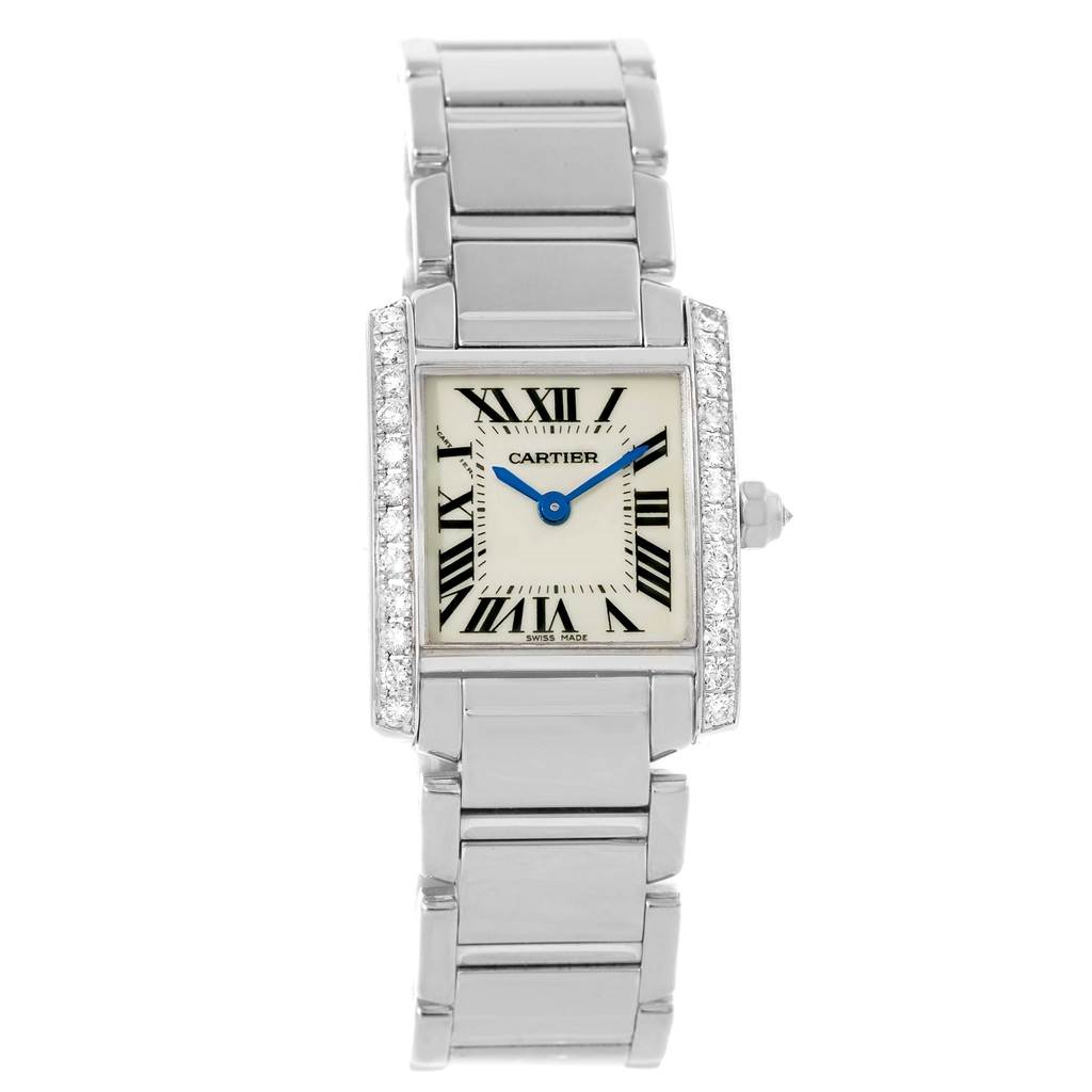 The Cartier Tank Française watch is shown from a top view, displaying its face, blue hands, Roman numerals, and metal bracelet.