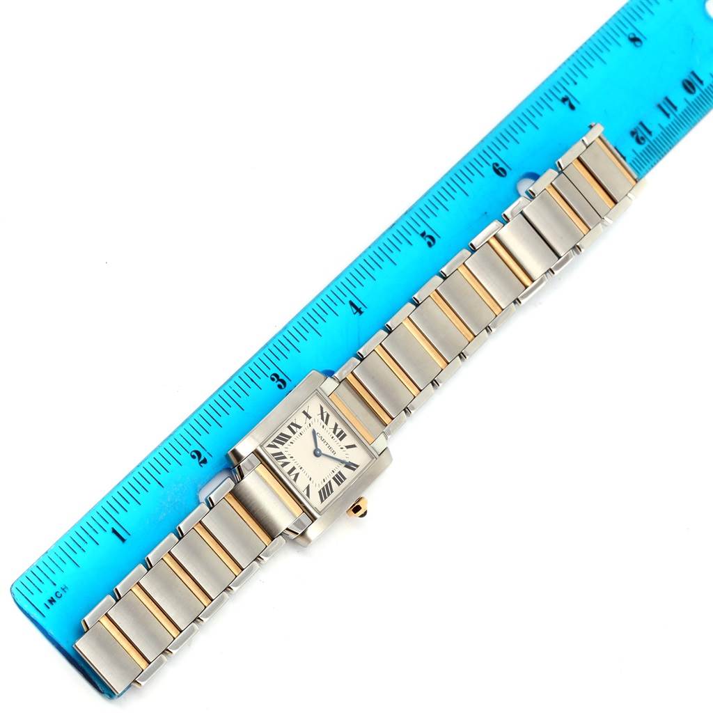 The image shows a top view of a Cartier Tank Française watch with a ruler for scale.