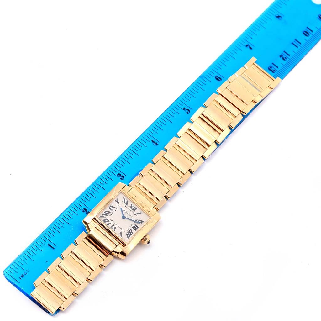 The Cartier Tank Francaise W50003N2 Women's Yellow Gold Silver Dial W50003N2 Women's Yellow Gold Silver Dial watch is displayed flat alongside a ruler, showing its face and gold bracelet.