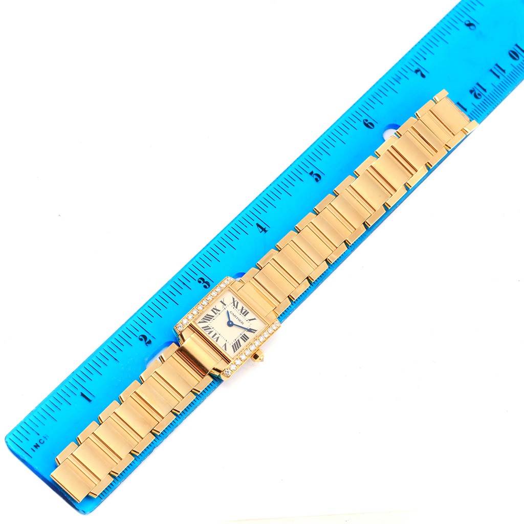 The image displays a Cartier Tank Française watch laid flat against a ruler, showing the watch face and gold bracelet.