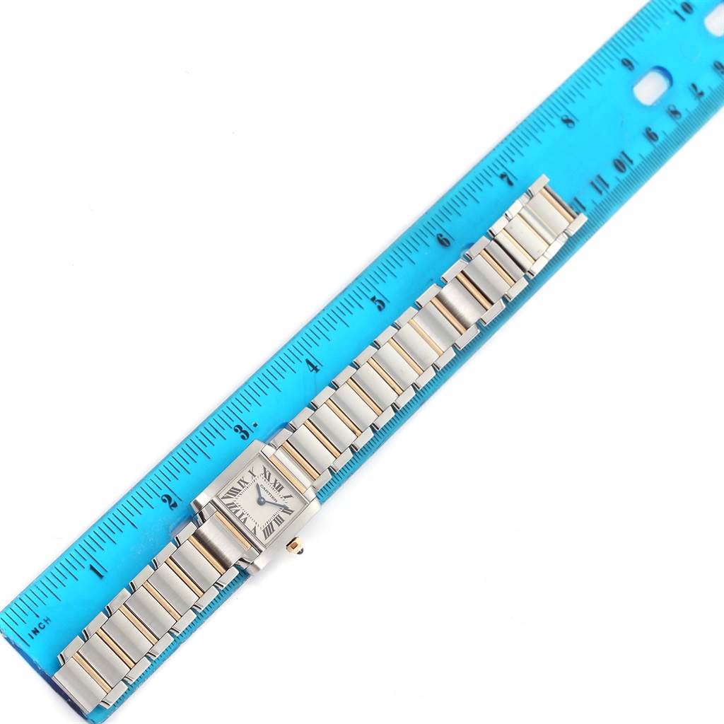 The image shows the entire Tank Française watch by Cartier laid flat next to a blue ruler for measurement.