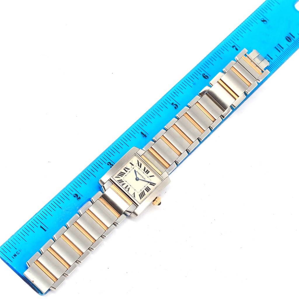 The image shows a top view of a Cartier Tank Francaise W2TA0003 Women's Steel and Gold (two tone) Silver Dial W2TA0003 Women's Steel and Gold (two tone) Silver Dial watch beside a blue ruler for scale.