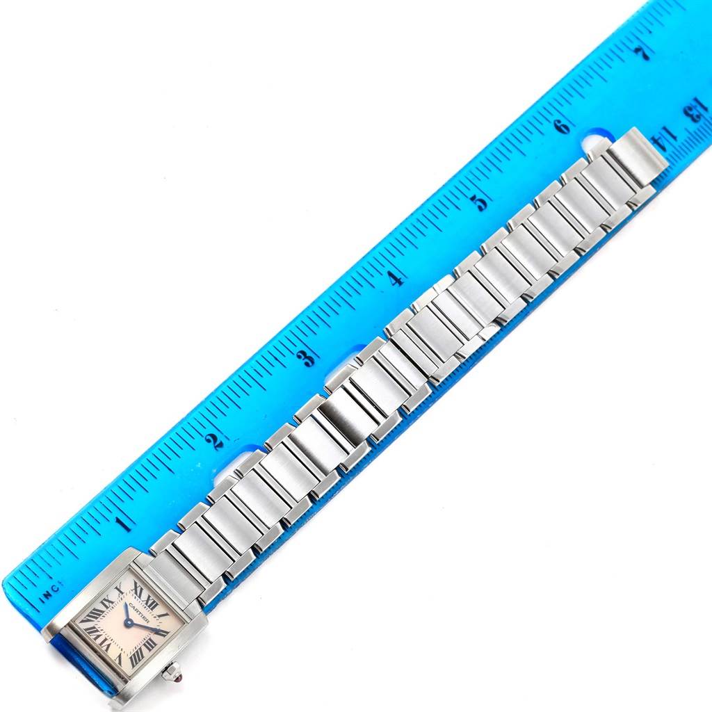 This image shows a Cartier Tank Française watch laid flat next to a ruler, displaying the watch face and metal bracelet.