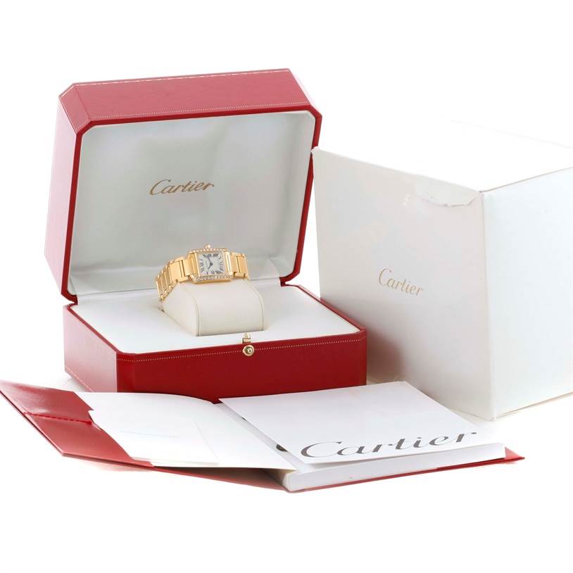The Cartier Tank Francaise WE1001R8 Women's Yellow Gold Silver Dial WE1001R8 Women's Yellow Gold Silver Dial watch is shown in an open red box, along with its white outer box and associated booklets.