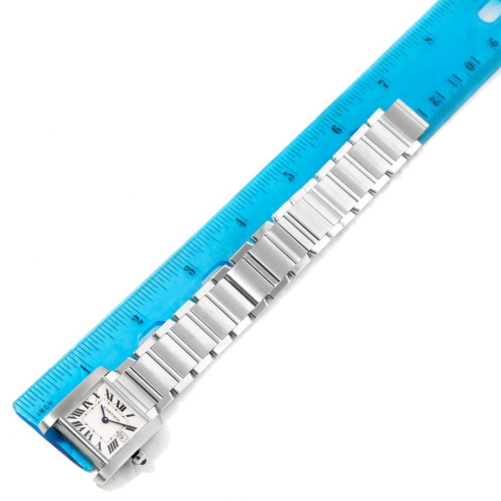 The Tank Francaise model by Cartier is shown from a top-down angle, displaying the watch face and bracelet placed next to a ruler.