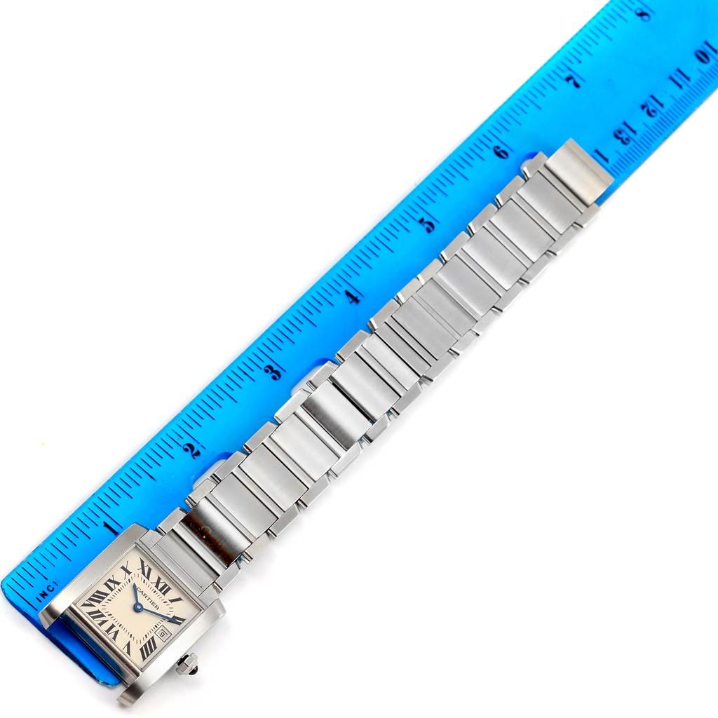 The Cartier Tank Francaise W51011Q3 Women's Stainless Steel Silver Dial W51011Q3 Women's Stainless Steel Silver Dial watch is laid flat next to a ruler, showcasing its face and the entire metal bracelet.