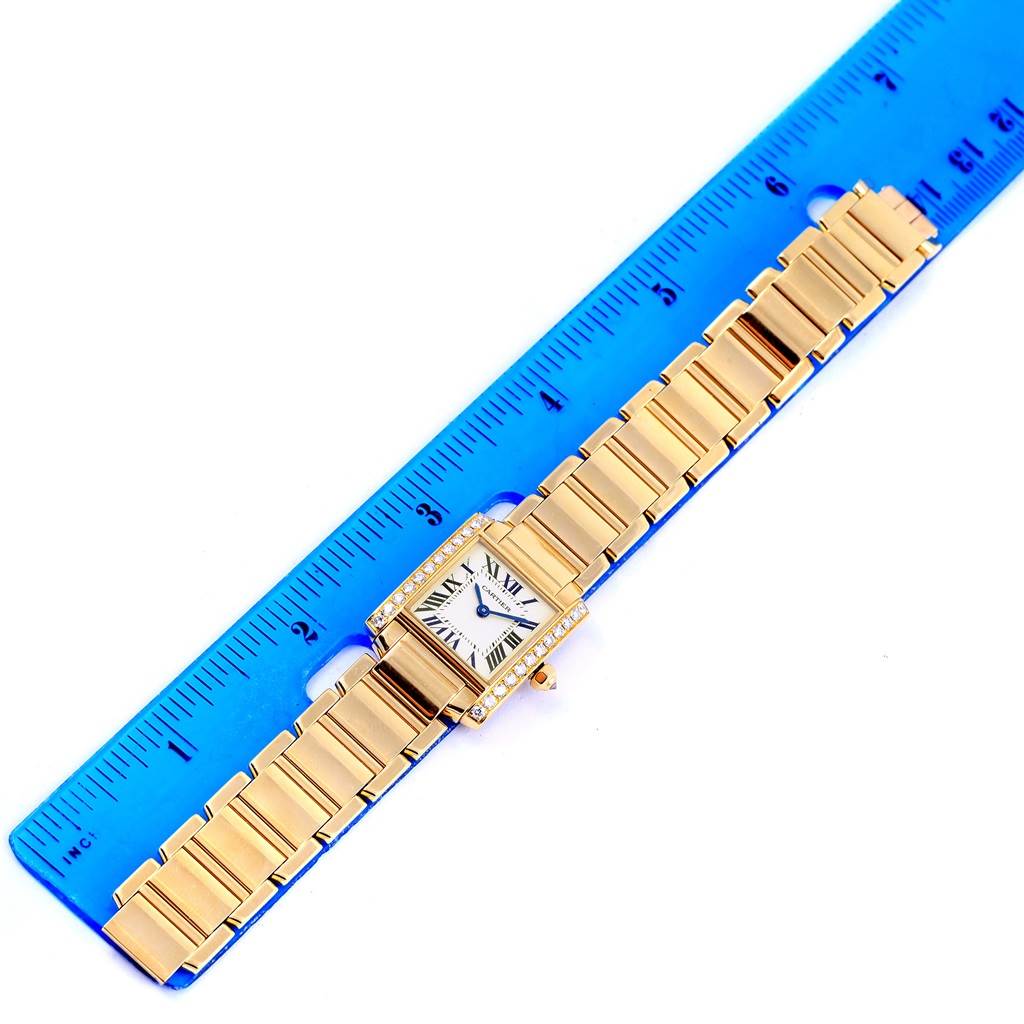 The image shows a Cartier Tank Francaise WE1001R8 Women's Yellow Gold Silver Dial WE1001R8 Women's Yellow Gold Silver Dial watch from a top-down angle, placed next to a blue ruler for scale.