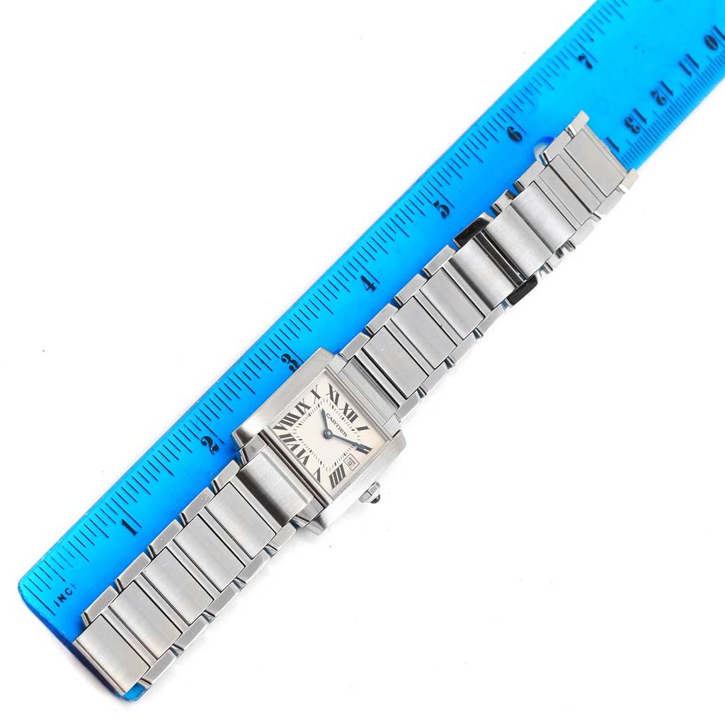 The image shows a Cartier Tank Française watch laid flat next to a blue ruler.