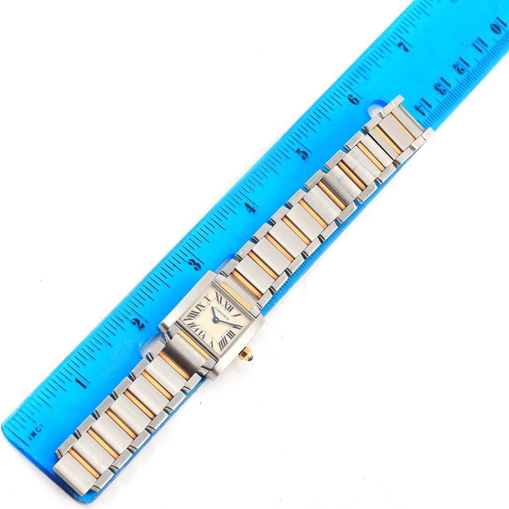 The image shows an overhead view of a Cartier Tank Francaise W51007Q4 Women's Steel and Gold (two tone) Silver Dial W51007Q4 Women's Steel and Gold (two tone) Silver Dial watch placed next to a blue ruler.