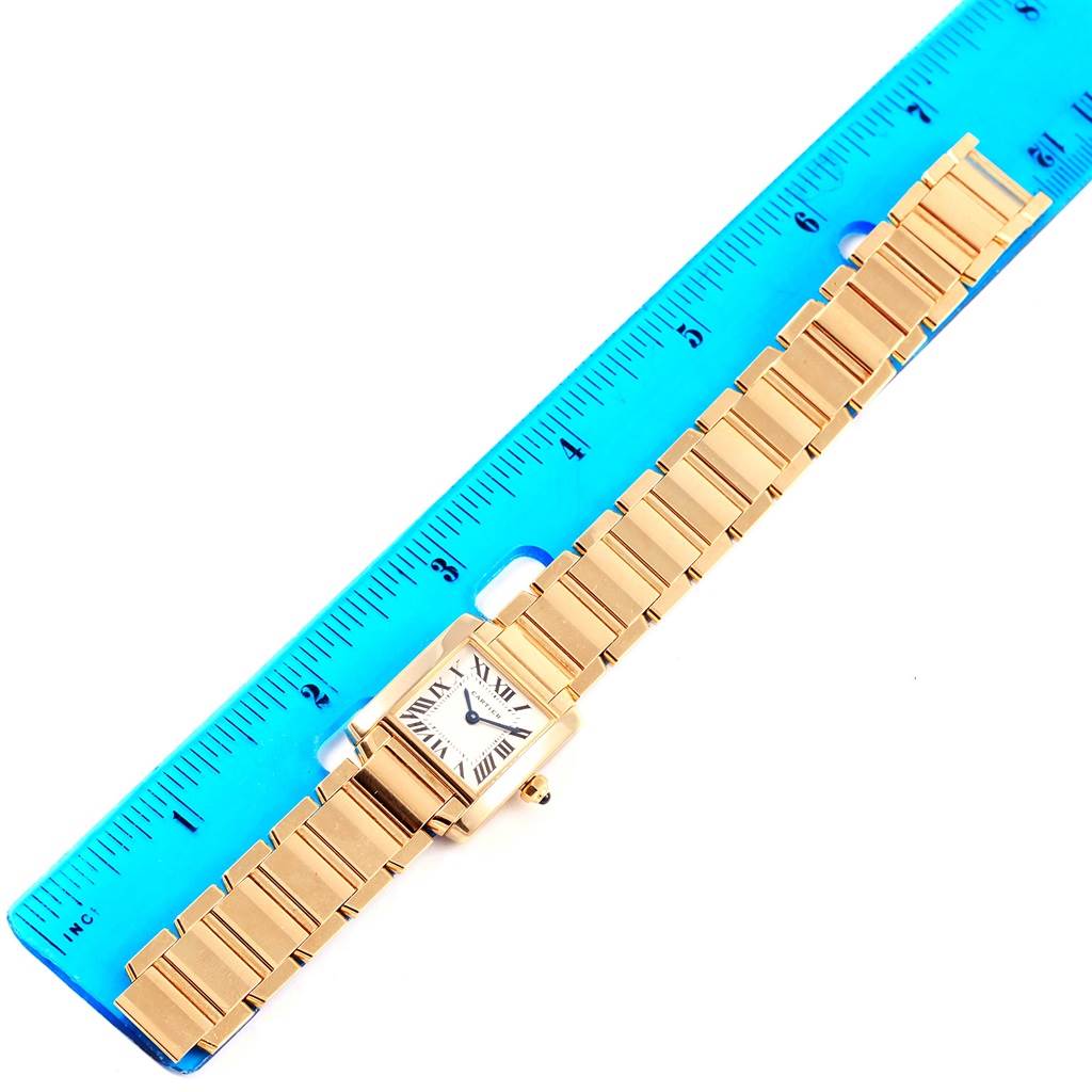 The Cartier Tank Francaise W50002N2 Women's Yellow Gold Silver Dial W50002N2 Women's Yellow Gold Silver Dial watch is shown from a top-down angle, highlighting the gold bracelet and rectangular face next to a ruler.