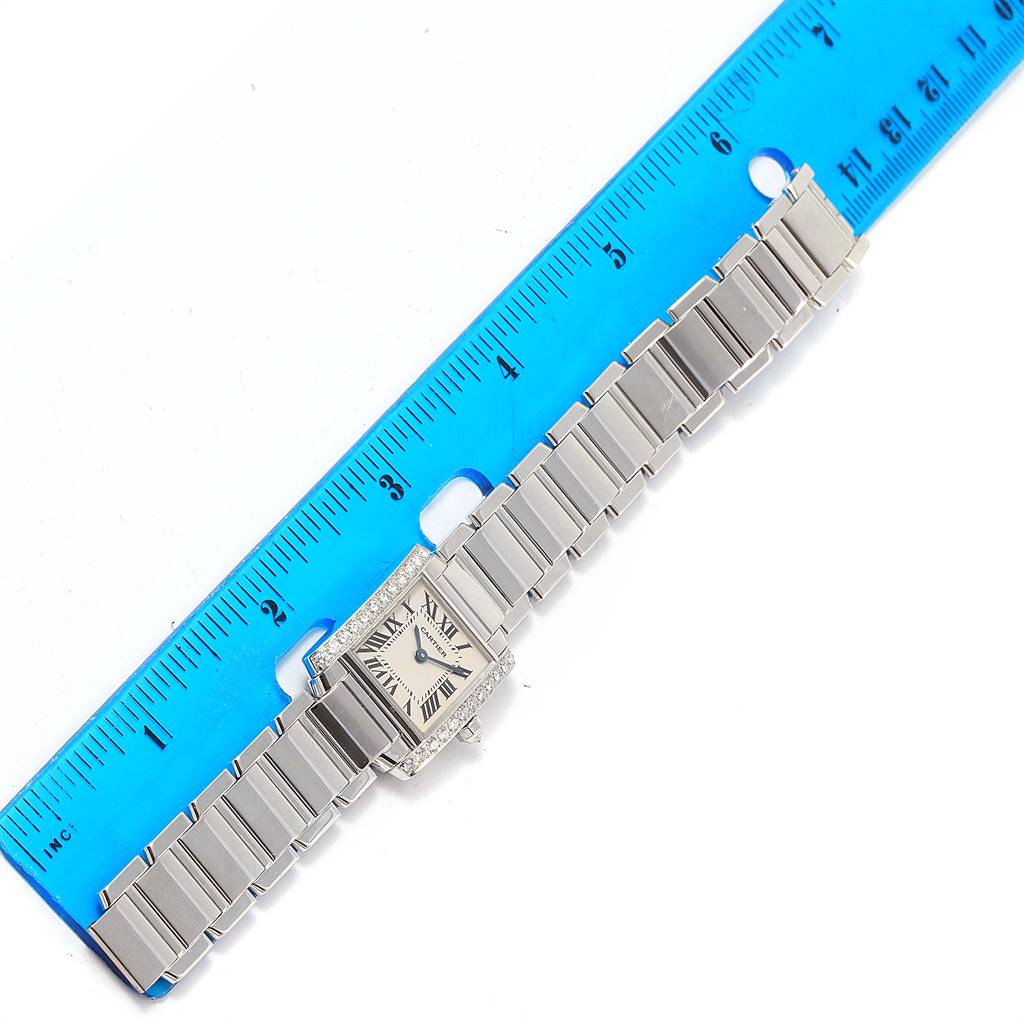 The Cartier Tank Française watch is displayed flat, showing its rectangular face and full metal bracelet alongside a ruler for scale.