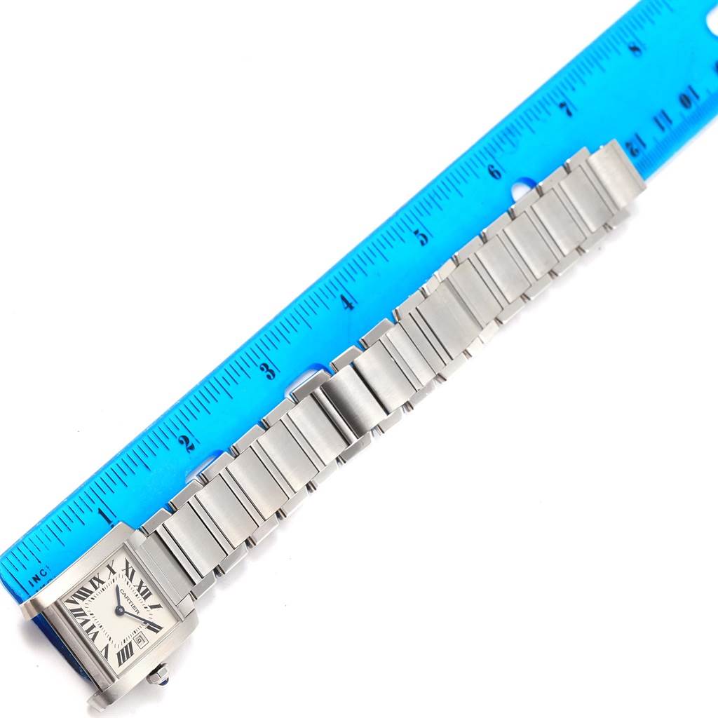 The image shows a Cartier Tank Francaise W51011Q3 Women's Stainless Steel Silver Dial W51011Q3 Women's Stainless Steel Silver Dial watch lying flat next to a blue ruler, highlighting its stainless steel bracelet and rectangular face.