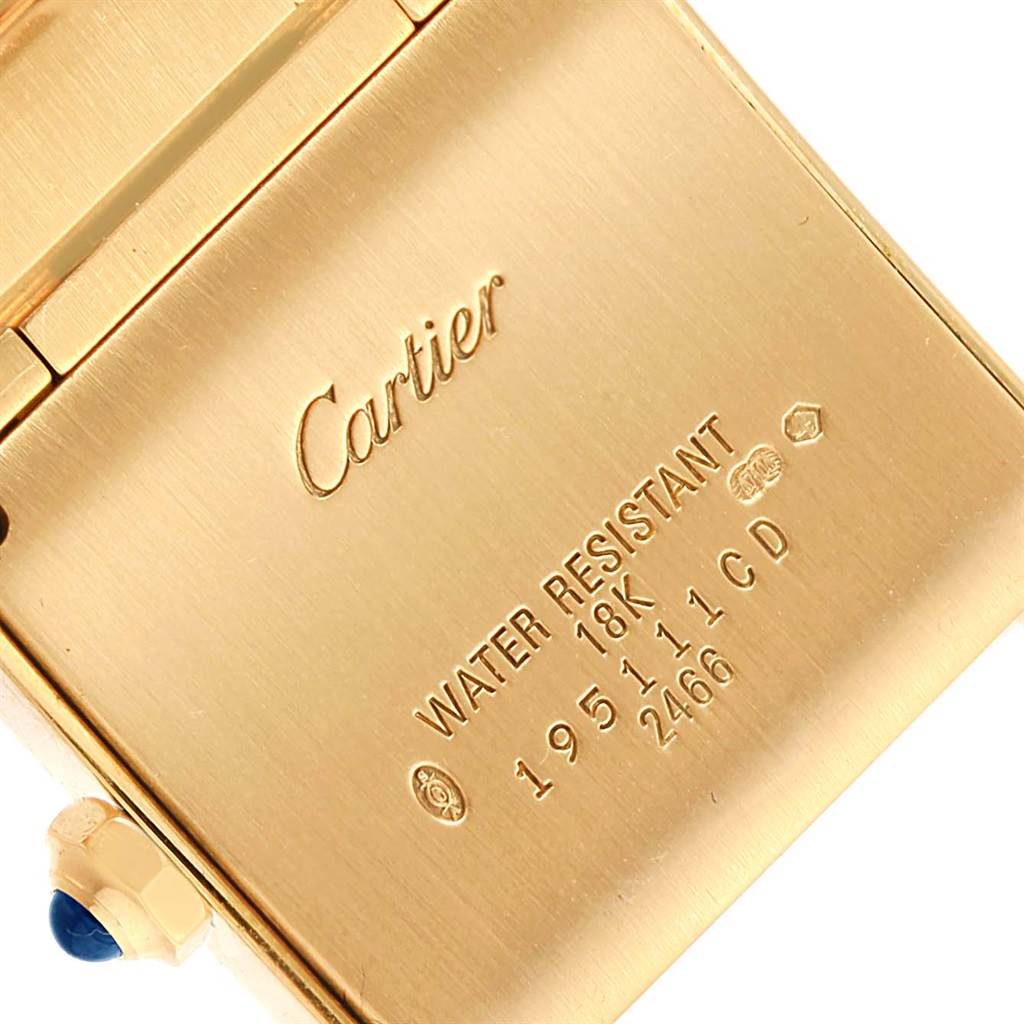 The image shows the back case of a Cartier Tank Francaise W50014N2 Women's Yellow Gold Silver Dial W50014N2 Women's Yellow Gold Silver Dial watch, highlighting its inscriptions and part of its bejeweled crown.