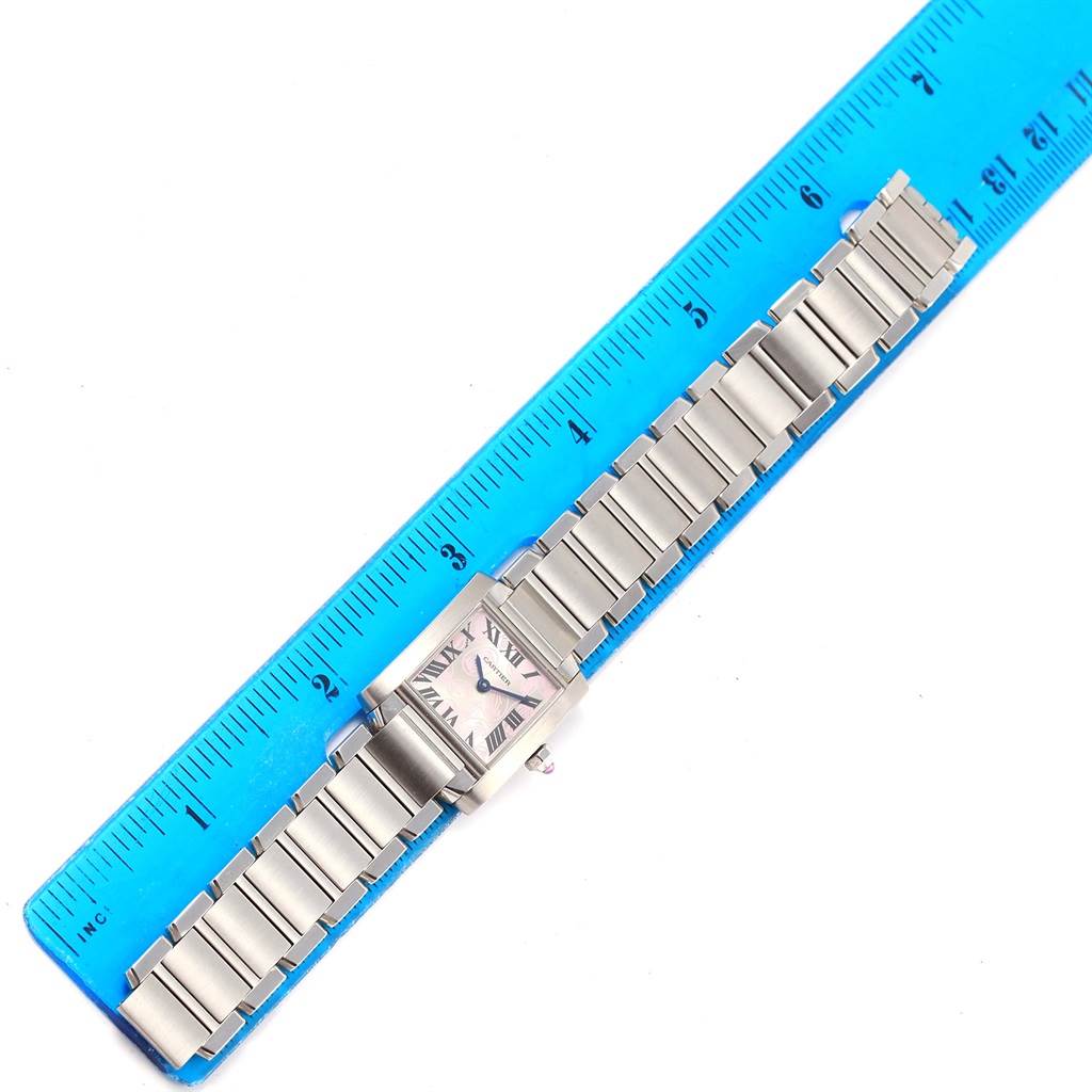 This image shows a Cartier Tank Française watch placed alongside a blue ruler for measurement.