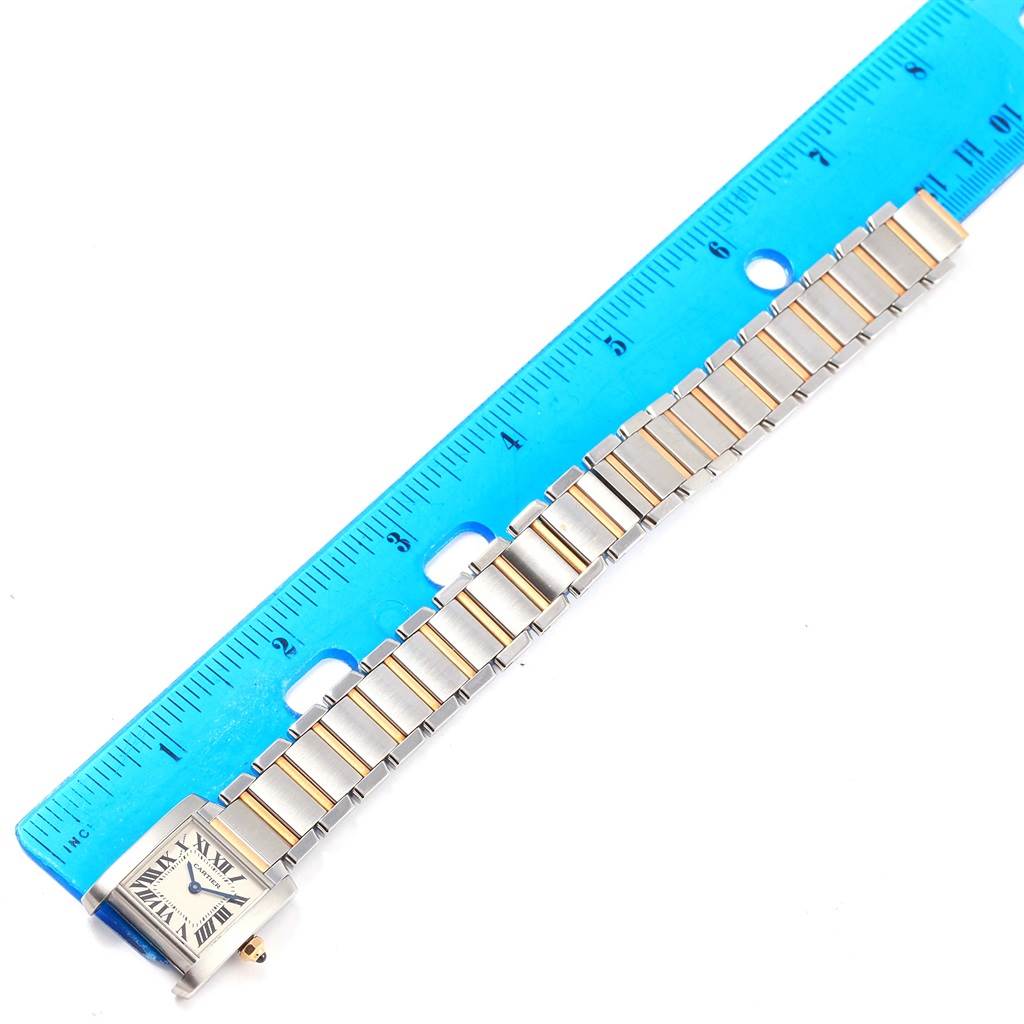 The Cartier Tank Francaise W51007Q4 Women's Steel and Gold (two tone) Silver Dial W51007Q4 Women's Steel and Gold (two tone) Silver Dial watch is shown laid flat, highlighting its face and full metal band next to a blue ruler for scale.