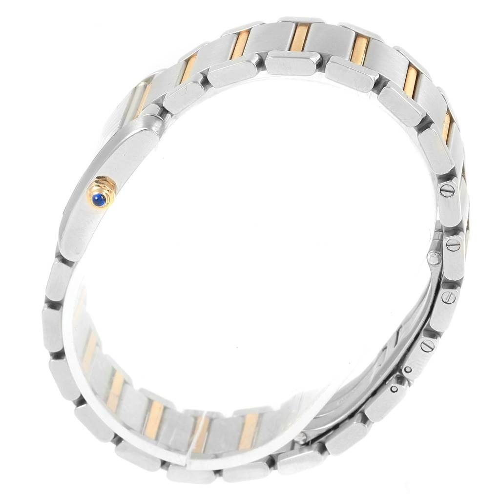 The image shows the side view of a Cartier Tank Française watch, highlighting its metal bracelet and crown with a blue cabochon.