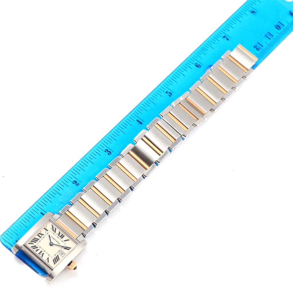 The image shows a Cartier Tank Francaise W51012Q4 Women's Steel and Gold (two tone) Silver Dial W51012Q4 Women's Steel and Gold (two tone) Silver Dial watch laid flat next to a blue ruler, showcasing the watch face and band.