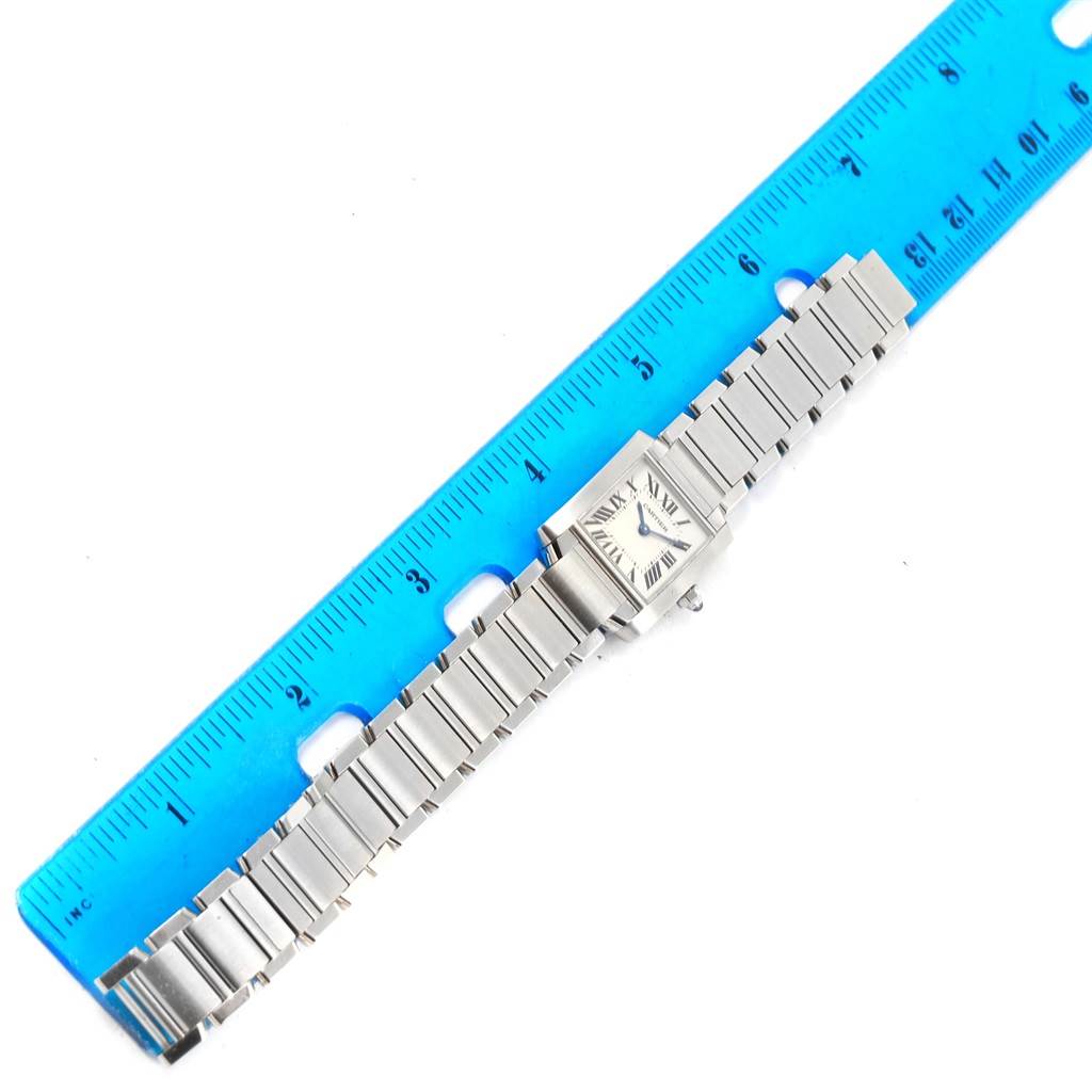 The image shows a Cartier Tank Française watch lying flat beside a blue ruler, displaying the watch face and bracelet in full length.