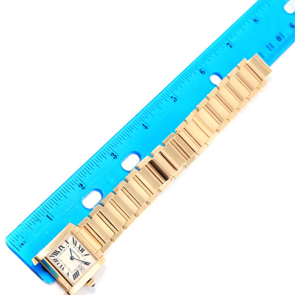 The image shows a Cartier Tank Française watch placed next to a blue ruler, displaying the front view of its face and band.