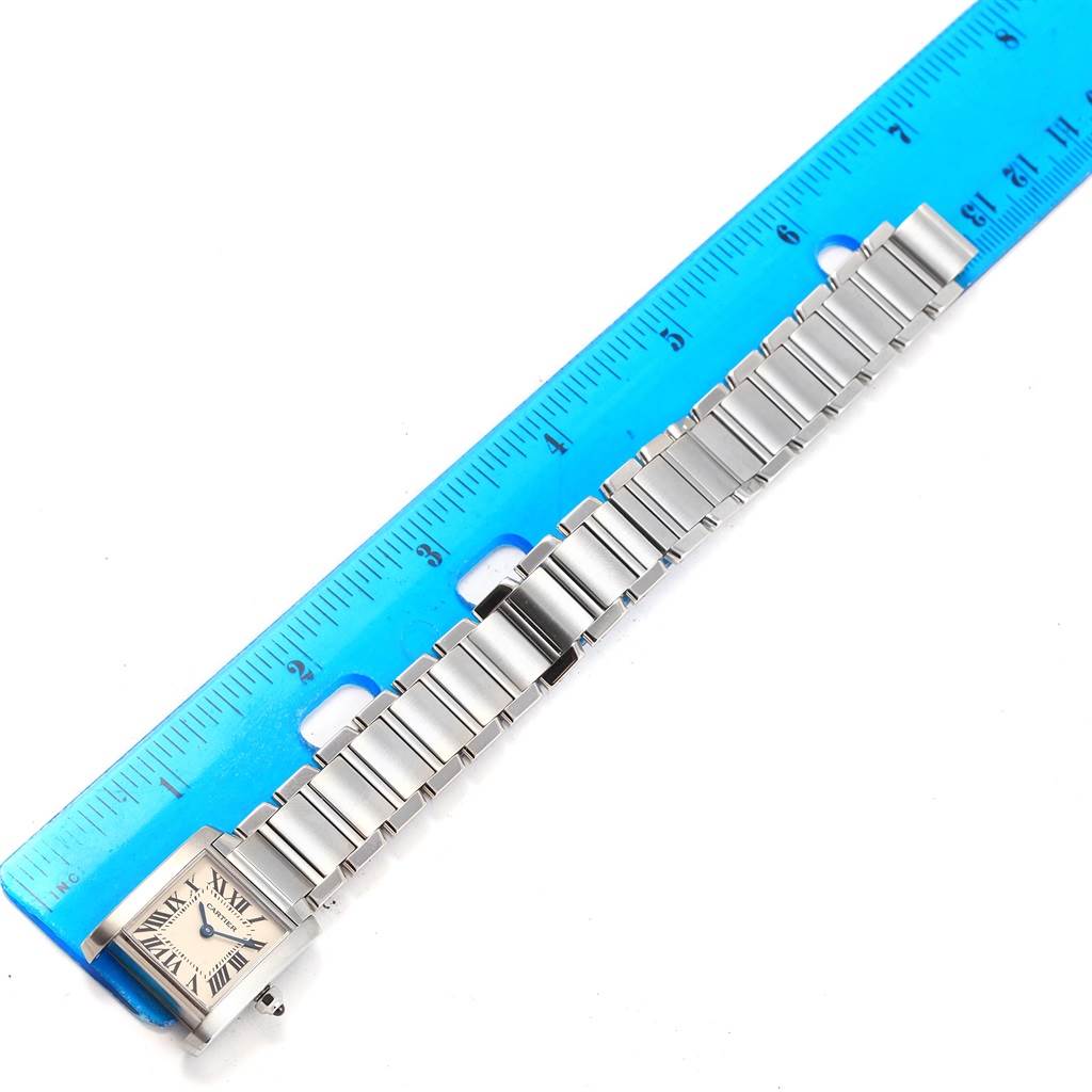 The image shows a top-down view of a Cartier Tank Française watch and its bracelet, next to a ruler for scale.