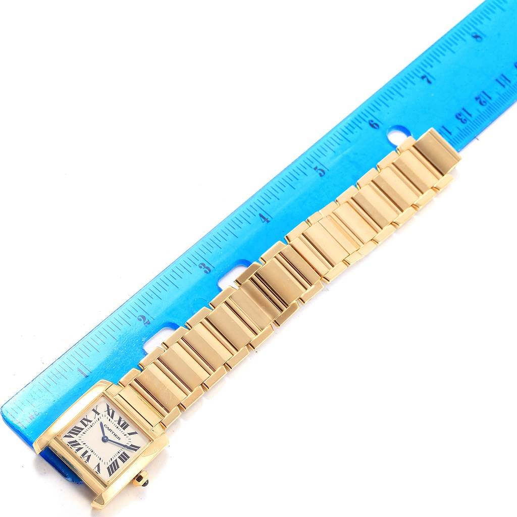 The Cartier Tank Française watch is shown lying flat next to a blue ruler, displaying its face and bracelet.