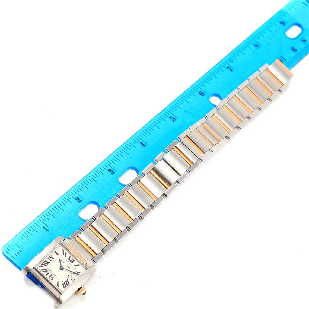 The image shows a Cartier Tank Francaise W51012Q4 Women's Steel and Gold (two tone) Silver Dial W51012Q4 Women's Steel and Gold (two tone) Silver Dial watch laid flat next to a blue ruler, highlighting the watch face and metal bracelet.