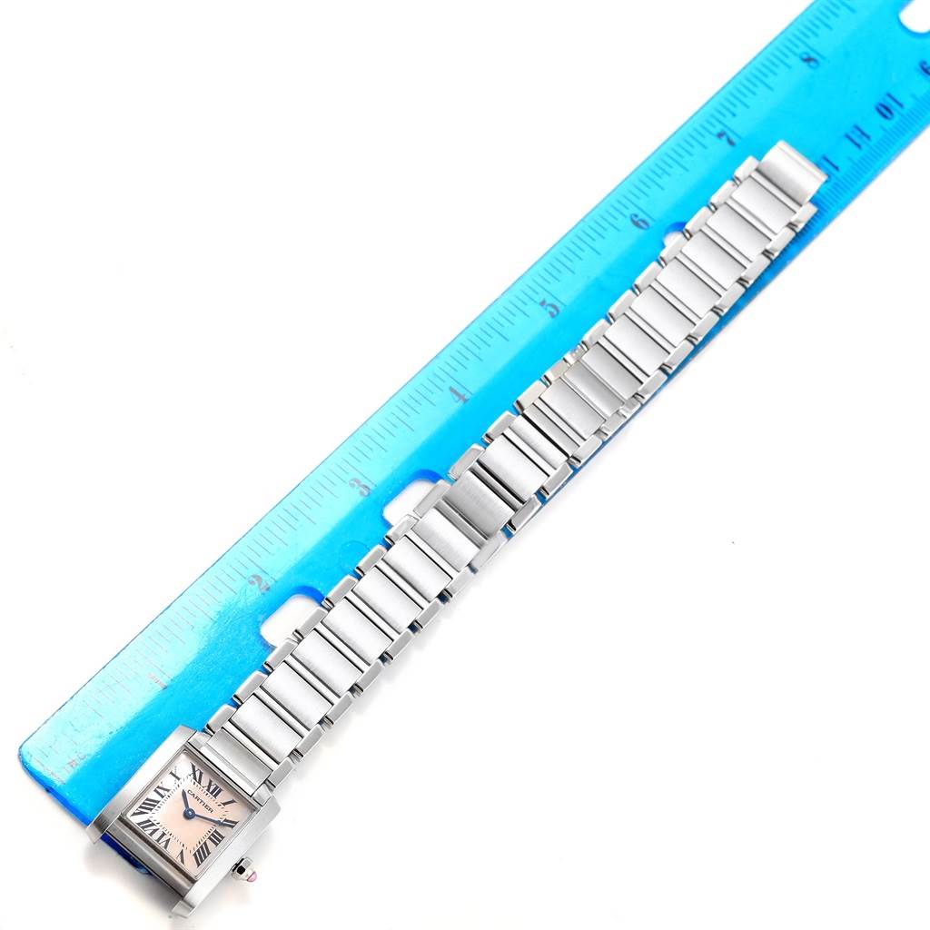 The image shows a Tank Francaise model by Cartier with its stainless steel bracelet laid out next to a blue ruler.