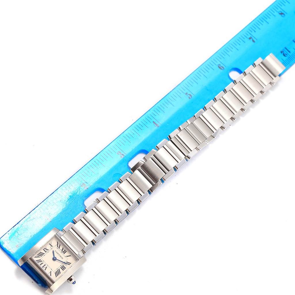 The image shows a Cartier Tank Française watch horizontally aligned next to a ruler, displaying its face and full metal bracelet.