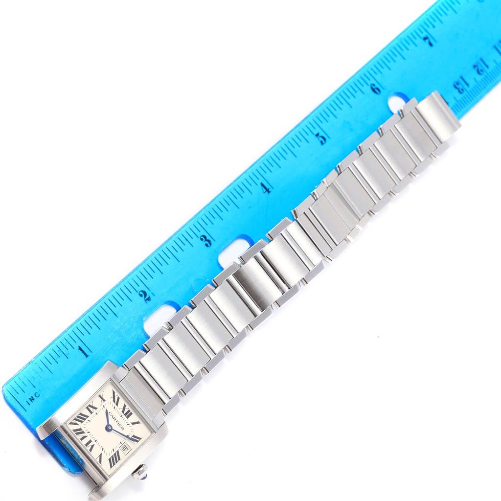 The image shows a top-down view of a Cartier Tank Francaise W51011Q3 Women's Stainless Steel Silver Dial W51011Q3 Women's Stainless Steel Silver Dial watch, displaying its face, bracelet, and a blue ruler for scale.