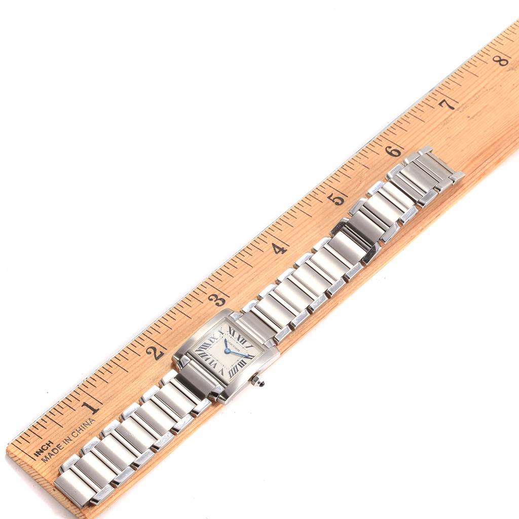 The watch, a Cartier Tank Française model, is shown from an overhead angle, highlighting its full metal bracelet and face.