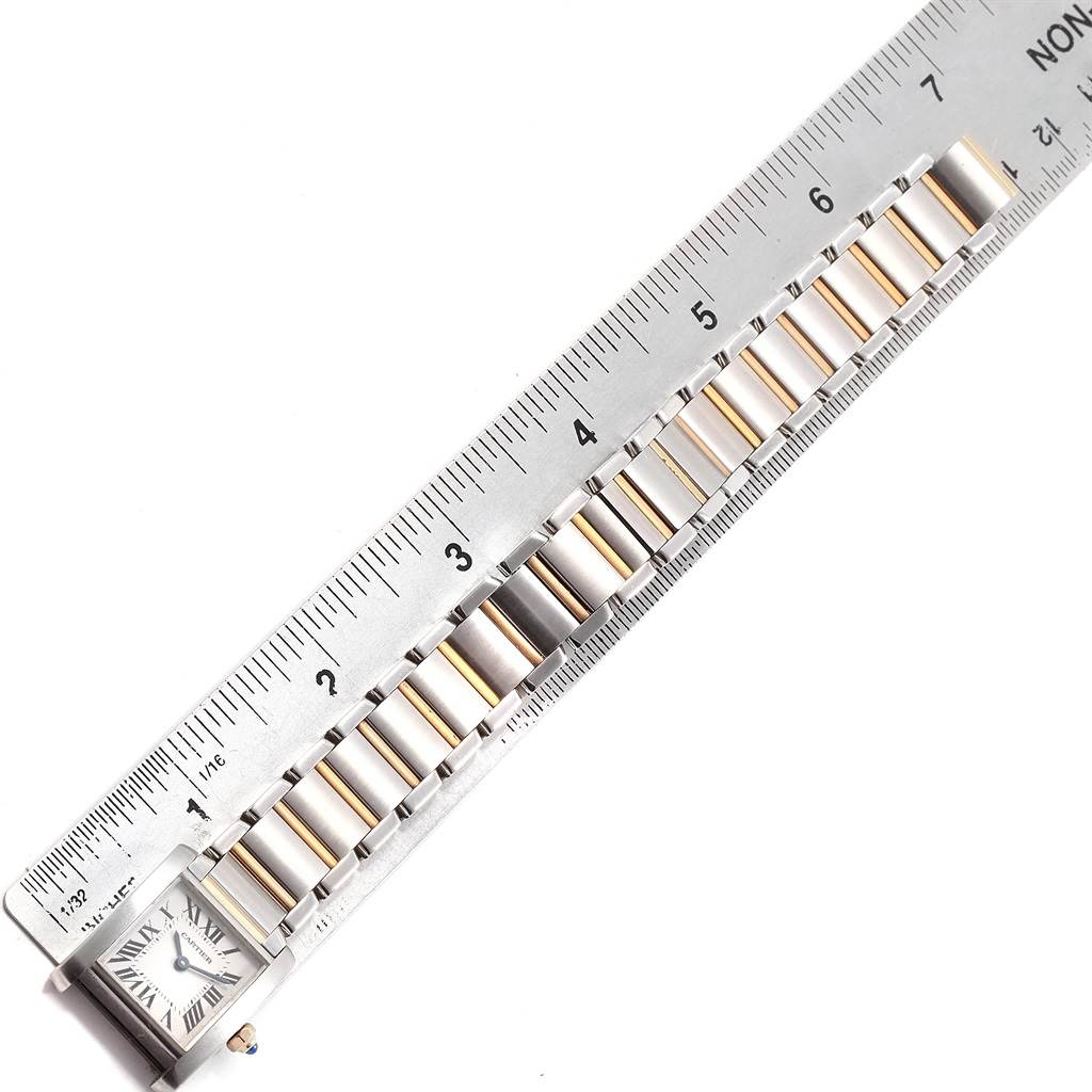 The Tank Francaise watch by Cartier is shown from a top view, highlighting its bracelet and a portion of the face beside a ruler.