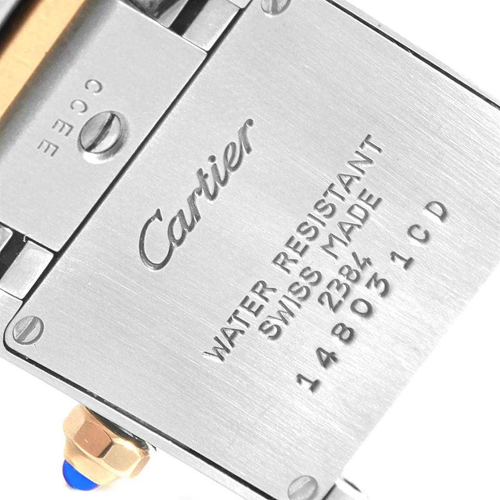 The image shows the back casing of a Cartier Tank Francaise W51007Q4 Women's Steel and Gold (two tone) Silver Dial W51007Q4 Women's Steel and Gold (two tone) Silver Dial watch, highlighting its engravings and part of the crown with a blue gemstone tip.