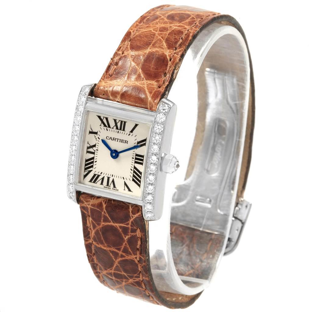 The Cartier Tank Française watch is shown from a slightly tilted angle, showcasing its face, brown leather strap, and diamond-studded bezel.