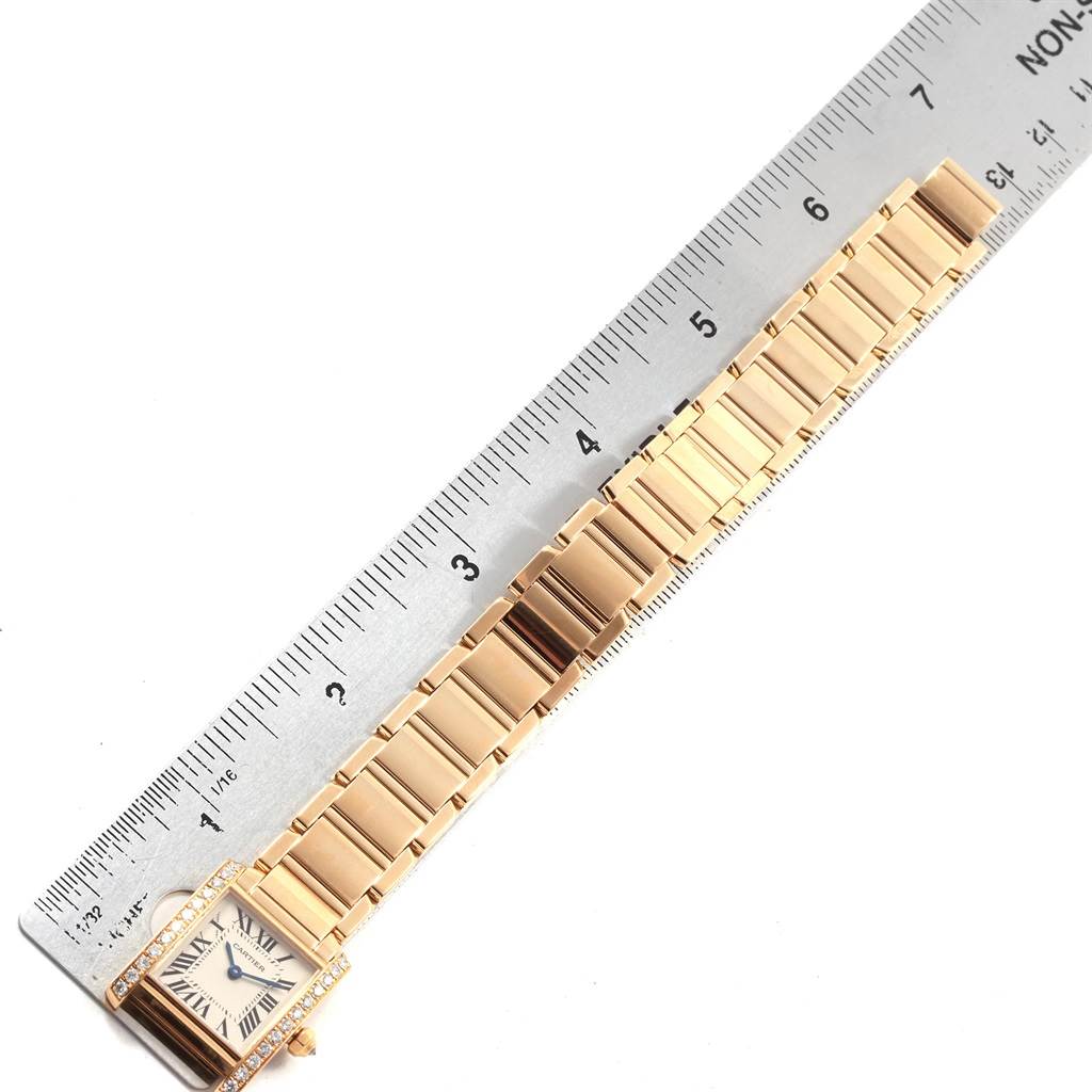 This image shows a Cartier Tank Française watch with a metallic band laid next to a ruler for size reference.