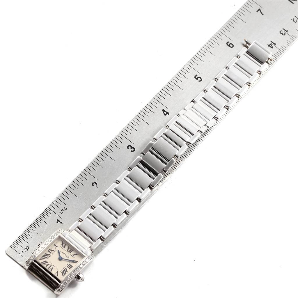 The image shows a Cartier Tank Française watch with its full metal bracelet aligned next to a ruler for measurement.