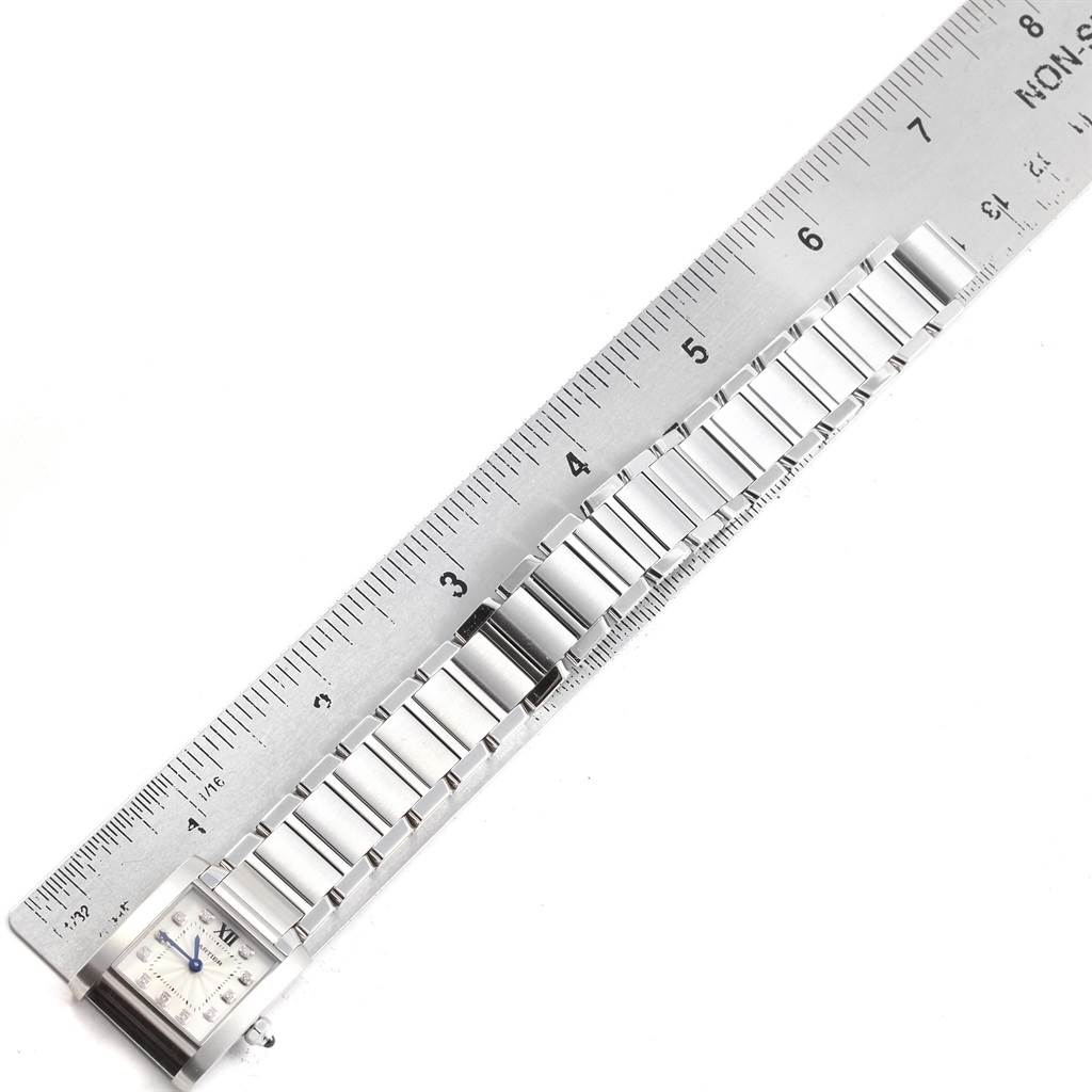 The image shows a Cartier Tank Francaise WE110006 Women's Stainless Steel Silver Dial WE110006 Women's Stainless Steel Silver Dial watch laid flat next to a ruler, highlighting its face and metallic strap.