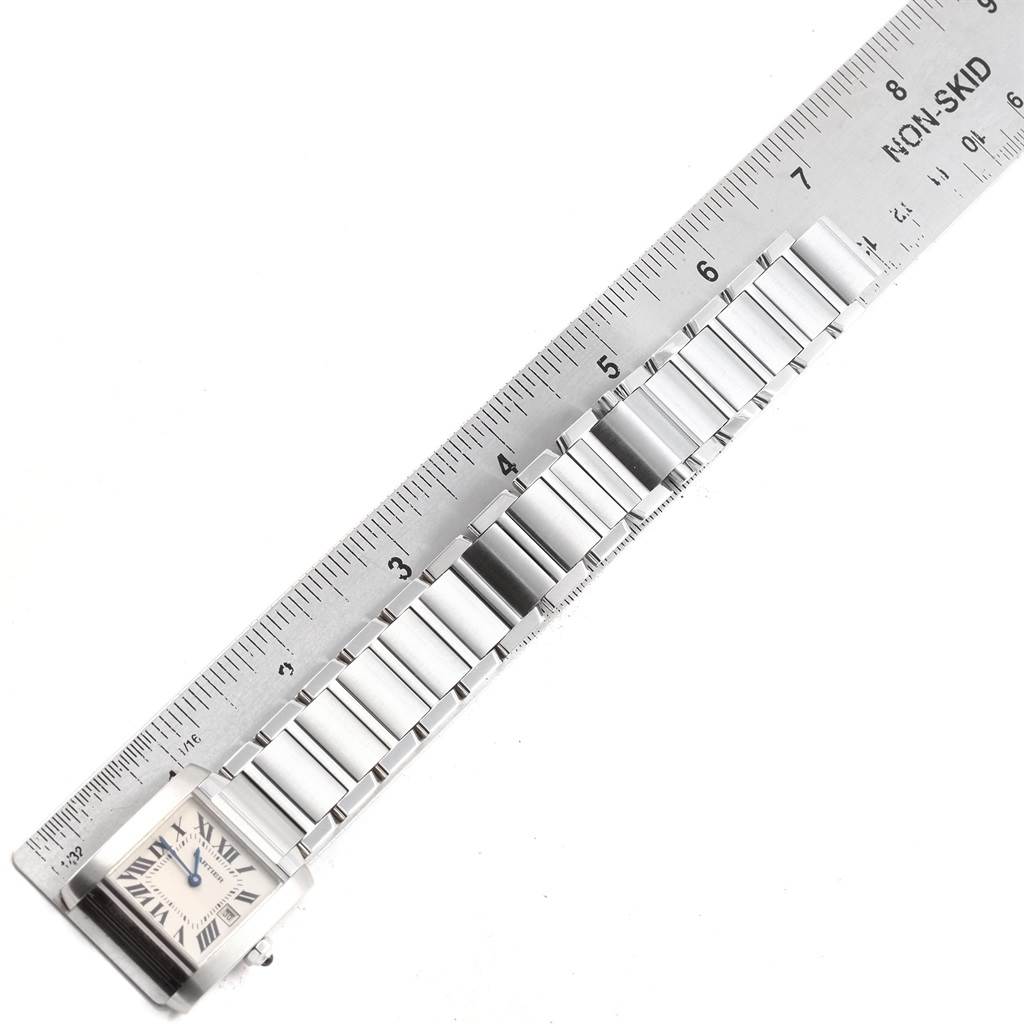 The image shows the bracelet and face of a Cartier Tank Française watch placed alongside a ruler for measurement.